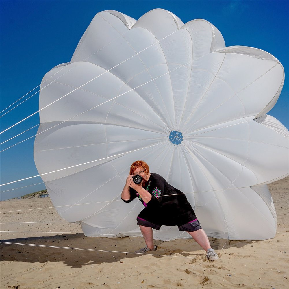 Jeanette Seidelmeyer mit Kamera vor einem Fallschirm am Strand